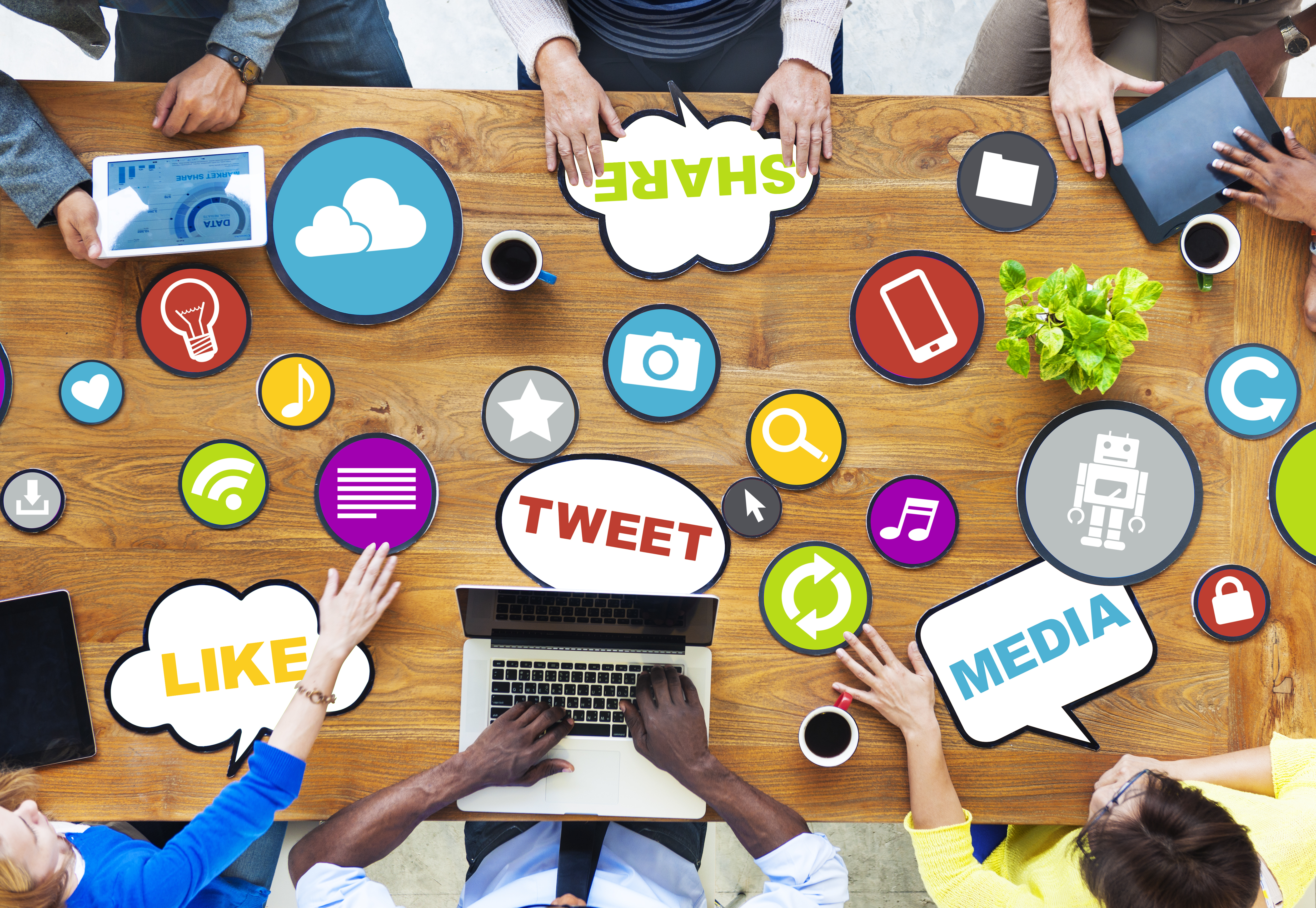 6 people gathered at a table using devices to Share, Media, Tweet and Like